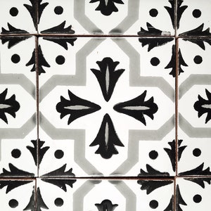 May include: Black and white patterned tile with a geometric design. The tile has a white background with black floral shapes and dots.