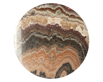 Puede incluir: Una losa de piedra redonda con un patrón único. La superficie muestra capas de color, incluyendo tonos de marrón, beige, gris y rojo. El diseño de la piedra se asemeja a olas fluidas, creando una textura visualmente atractiva.