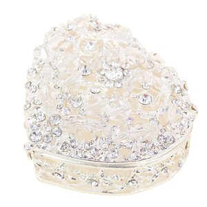 May include: A silver heart-shaped trinket box with a decorative design of clear rhinestones.