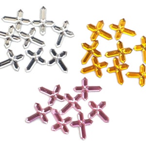 May include: Assortment of cross-shaped rhinestones in silver, gold, and pink.