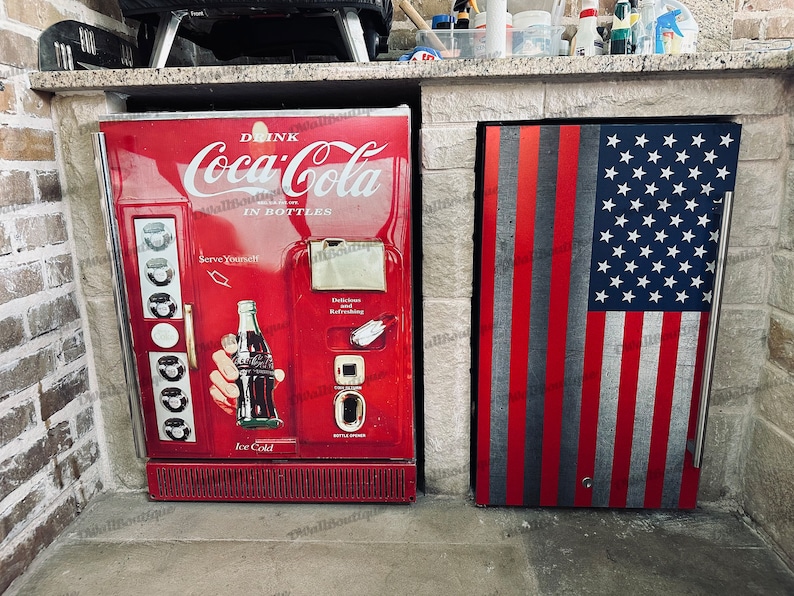 May include: Two red refrigerators side-by-side. The left refrigerator has a Coca-Cola logo and the text "Drink Coca-Cola in Bottles". The right refrigerator has an American flag design.