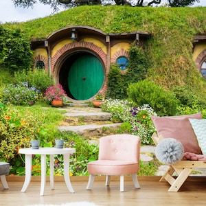 Pode incluir: Uma porta verde com um arco redondo leva a uma toca de hobbit, uma pequena casa redonda constru&iacute;da em uma colina gramada. A casa tem um exterior de tijolo e um telhado de palha. H&aacute; flores e plantas crescendo ao redor da casa.