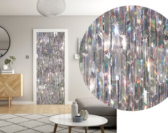 May include: A silver iridescent curtain made of thin strips of plastic. The curtain is hanging in a doorway in a living room. The curtain is made of many small, reflective pieces that create a shimmering effect.