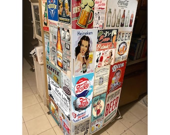 May include: A white refrigerator covered in numerous vintage-style metal signs and advertisements for various beer and soda brands, including Coca-Cola, Pepsi, Heineken, and Miller High Life, featuring colorful illustrations of bottles, glasses, and people.