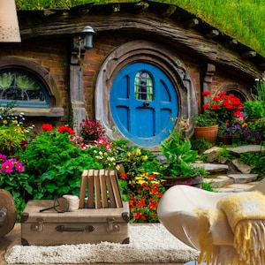 Pode incluir: Uma casa de hobbit de sonho com uma porta redonda azul, rodeada de vegeta&ccedil;&atilde;o exuberante e flores coloridas. Uma cadeira branca com um cobertor amarelo fica em primeiro plano.