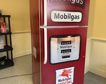 May include: A red refrigerator designed to resemble a vintage Mobilgas fuel pump. The exterior features the Mobilgas logo, a white display panel with numerical counters, and a shield-shaped emblem depicting a red winged horse and the text Mobilgas SPECIAL.