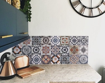 Puede incluir: Un salpicadero de cocina con un diseño de azulejos de patrones coloridos. Los azulejos son de varios colores, incluyendo azul, verde, rojo y amarillo. Los azulejos están dispuestos en un patrón geométrico. El salpicadero está sobre una encimera con una superficie similar al granito. Hay una tostadora y una tetera en la encimera.