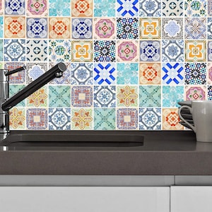 May include: A kitchen sink with a silver faucet and a backsplash of colorful patterned tiles. Two white ceramic mugs are on the counter.