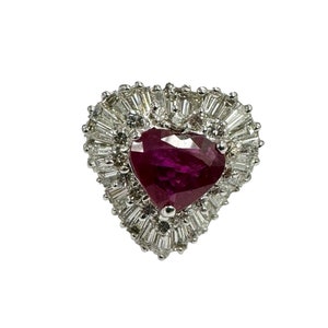 Może przedstawiać: Pierścionek z rubinem w kształcie serca z halo z diamentów o szlifie bagietkowym osadzonych w białym złocie.