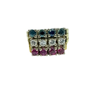 May include: A gold ring with three rows of gemstones. The top row has blue sapphires, the middle row has white diamonds, and the bottom row has pink rubies.