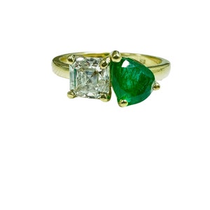以下が含まれることがあります： 正方形のダイヤモンドと洋梨型のエメラルドがセットされた金のリングです。