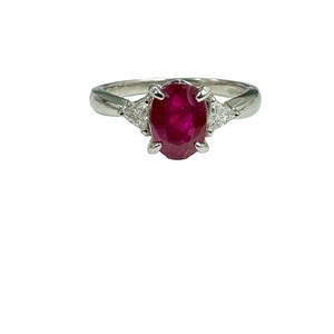 May include: A platinum ring with a red ruby gemstone and two smaller diamonds on either side.
