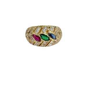 May include: A gold ring with a textured band, featuring three marquise-cut gemstones in red, green, and blue. The band is embellished with small, clear gemstones, creating a luxurious and eye-catching design. The ring is set against a white background.