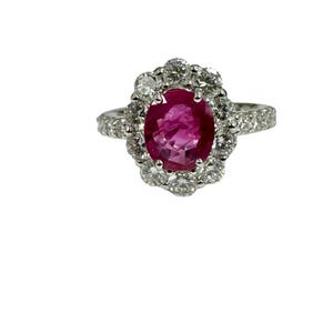 May include: A silver ring with a large oval ruby surrounded by a halo of smaller diamonds.
