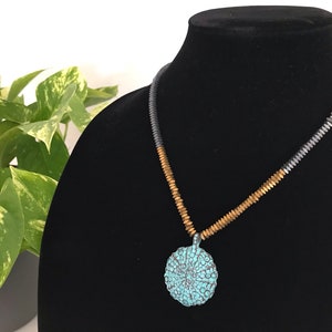 May include: A necklace with a turquoise blue pendant and a two-tone chain of gold and silver beads.