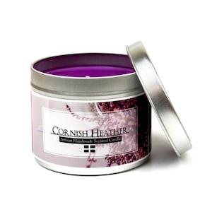 May include: A purple scented candle in a silver tin with a label that reads "Cornish Heather Artisan Handmade Scented Candle".