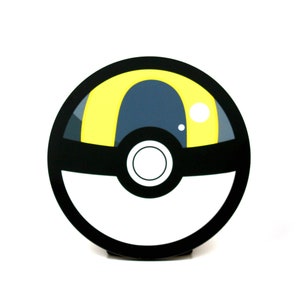 May include: A black and white Poke Ball with a yellow and gray center. The Poke Ball is a popular collectible item from the Pokemon franchise.