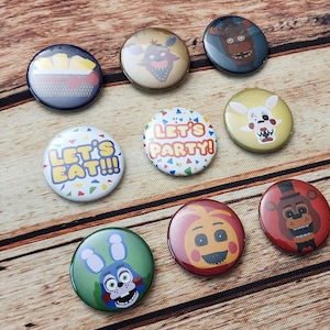 Peut inclure: Huit boutons ronds avec différents motifs. Les boutons représentent des personnages du jeu vidéo Five Nights at Freddy's. Les boutons comprennent un ours animatronique jaune, un lapin animatronique violet, un renard animatronique blanc, un ours animatronique brun, un poulet animatronique jaune, un lapin animatronique bleu, un ours animatronique rouge et un bouton avec le texte "Let's Party!"