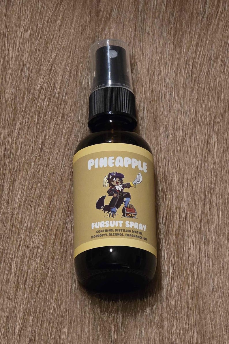 May include: A dark brown glass spray bottle with a black cap and a yellow label. The label reads "PINEAPPLE" above an illustration of a cartoon character. Below the illustration, the label reads "FURSUIT SPRAY".