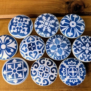 May include: Ten blue and white ceramic knobs with intricate floral and geometric patterns. The knobs are round and have a smooth, glossy finish.