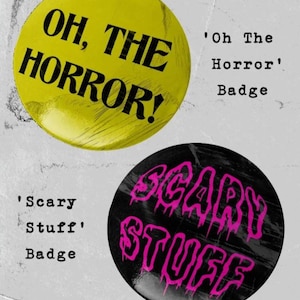Puede incluir: Dos botones redondos con pasador. El primer botón es amarillo con texto negro que dice "OH, THE HORROR!" El segundo botón es negro con texto rosa que gotea que dice "SCARY STUFF".