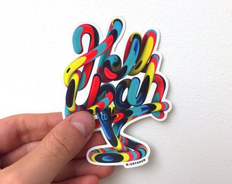 May include: A colorful sticker with the word "Hello" written in a 3D style with a blue, yellow, red, and black color scheme. The sticker has a white background and the artist's signature "M. URTASUN" is printed in the bottom right corner.