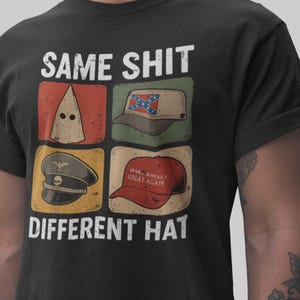 May include: Black t-shirt with the text "SAME SHIT DIFFERENT HAT" above four images of hats: a white hood, a Confederate flag hat, a military hat, and a red "Make America Great Again" hat.