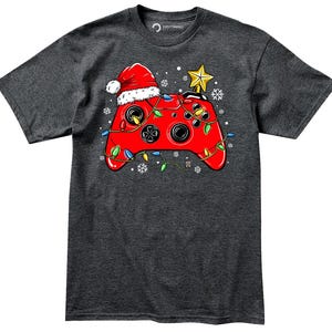 K&ouml;nnte beinhalten: Ein dunkelgraues T-Shirt mit einem roten Videospiel-Controller, der mit Weihnachtslichtern und einer Weihnachtsm&uuml;tze verziert ist. Der Controller ist mit einer gr&uuml;nen, roten und gelben Lichterkette umwickelt.