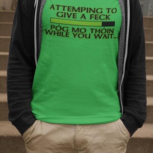 A person wearing a green t-shirt with text printed on it, standing on a set of stairs.