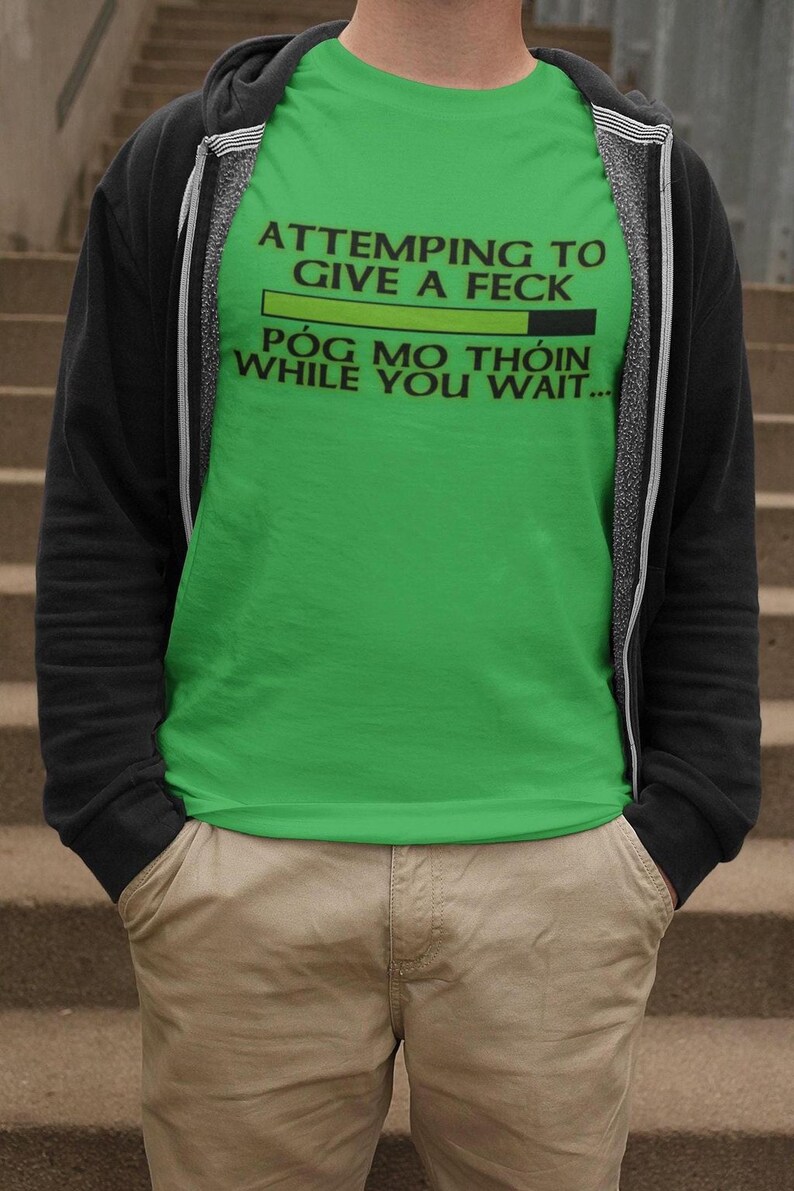 A person wearing a green t-shirt with text printed on it, standing on a set of stairs.