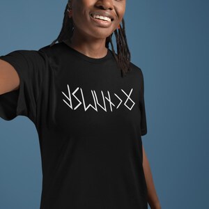 A smiling young woman wearing a black t-shirt with white text on it.