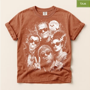 a t-shirt with a graphic design of a group of characters from the "Halloween" movie franchise, including Frankenstein's monster, Mary Shelley, and other iconic figures.