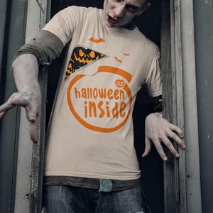 A man wearing a Halloween-themed t-shirt with the text "Halloween inside" is peeking out from behind a window frame.