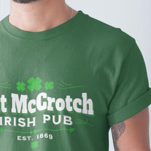 A man wearing a green t-shirt with white text and a shamrock design.