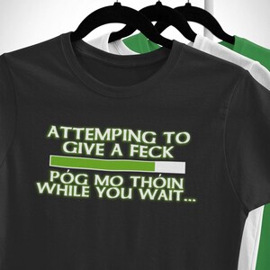 A black t-shirt with white text and a green progress bar on it, hanging on a clothing rack.