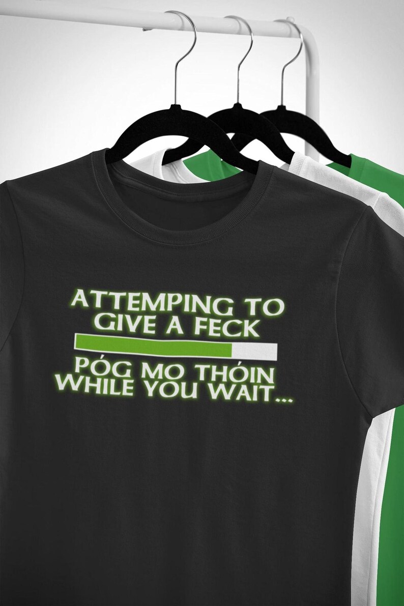 A black t-shirt with white text and a green progress bar on it, hanging on a clothing rack.