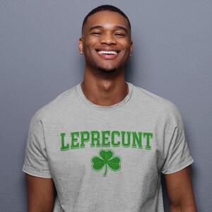 A smiling man wearing a grey t-shirt with the word "Leprecht" printed on it.