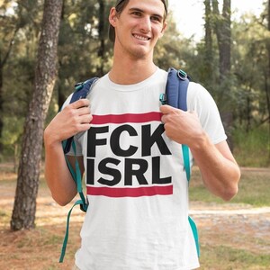 A man wearing a white t-shirt with the text "FCK ISRL" standing in a forested area.