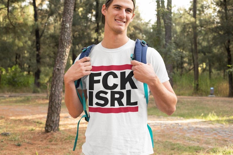 A man wearing a white t-shirt with the text "FCK ISRL" standing in a forested area.