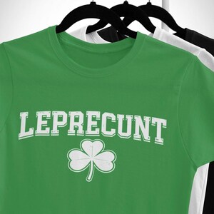 A green t-shirt with the text "Leprecht" and a white clover graphic printed on it, hanging on a clothing rack.