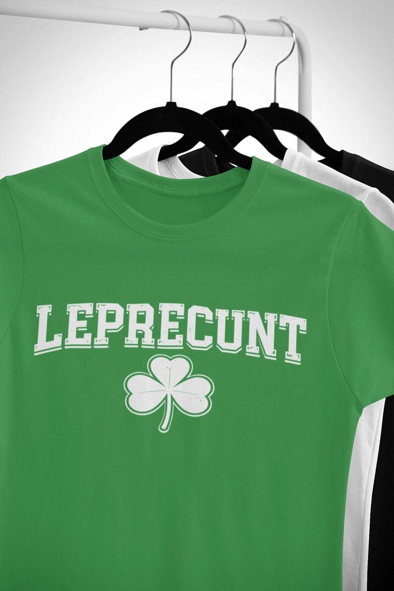 A green t-shirt with the text "Leprecht" and a white clover graphic printed on it, hanging on a clothing rack.