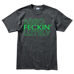 May include: Dark gray t-shirt with the words "ABSO FECKIN' LUTELY" printed in green. The shirt has a crew neck and short sleeves. The word "TEE" is printed on the tag.