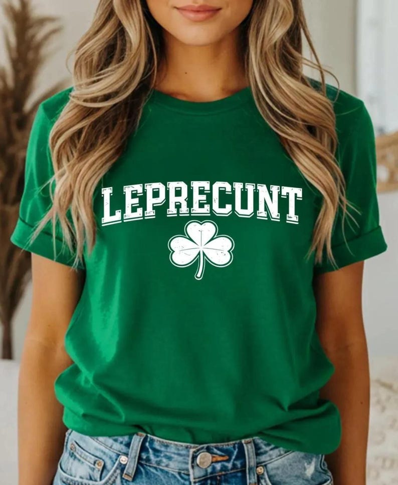 A woman wearing a green t-shirt with the word "LEPRECIUT" printed on it, standing in front of a mirror.