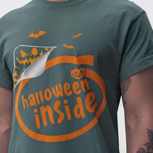 A person wearing a green t-shirt with the text "Halloween inside" printed on it.
