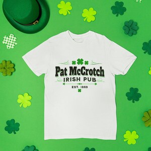 a white t-shirt with the text "Pat McGroch Irish Pub EST. 1969" printed on it, along with a green hat and various shamrocks scattered around the t-shirt.