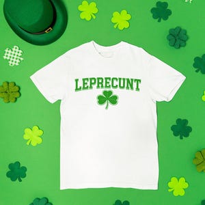 a white t-shirt with the word "Leprecht" printed on it, surrounded by various Leprecht-themed items such as shamrocks, hats, and other accessories.