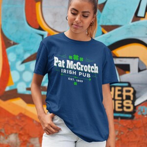A woman wearing a blue t-shirt with the text "Pat Groth Irish Pub EST.1869" stands in front of a colorful graffiti wall.