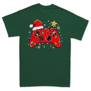 K&ouml;nnte beinhalten: Ein gr&uuml;nes T-Shirt mit einem roten Videospiel-Controller, der einen Weihnachtsmann-Hut und Weihnachtslichter tr&auml;gt. Der Controller ist mit einem Stern oben drauf verziert.