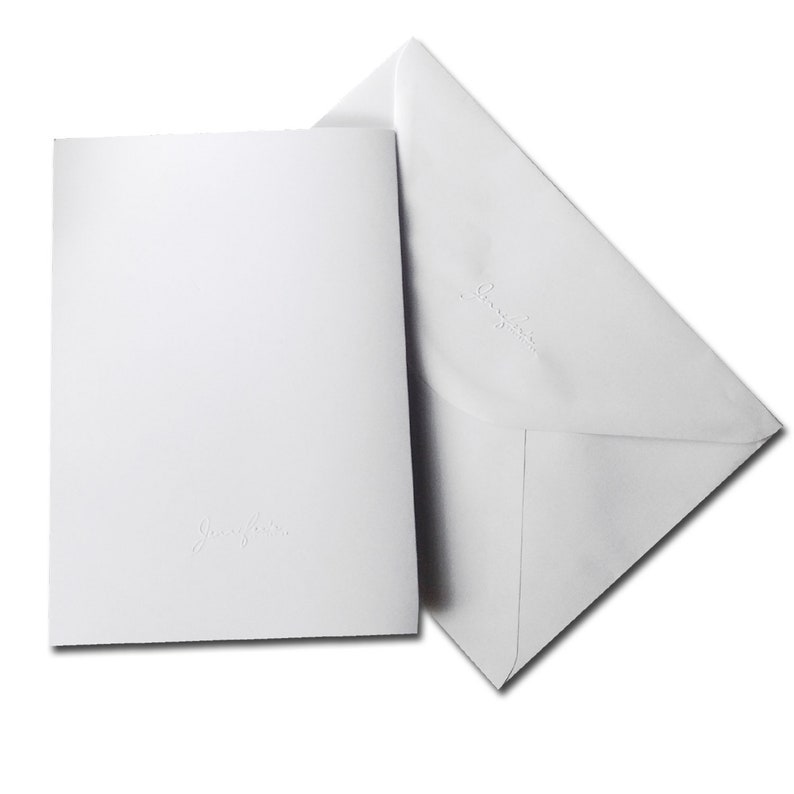 Op de afbeelding: Twee witte enveloppen met het woord "Greetings" erop gegraveerd.