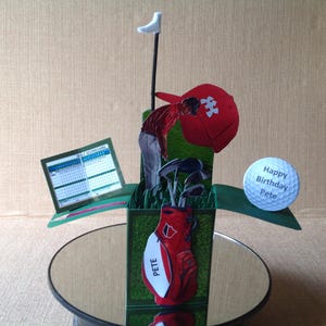 May include: A pop-up birthday card with a golf theme, showing a golfer, golf bag, scorecard, and golf ball. The golf ball has the text "Happy Birthday Pete". The golf bag is red with the name "Pete" on it.